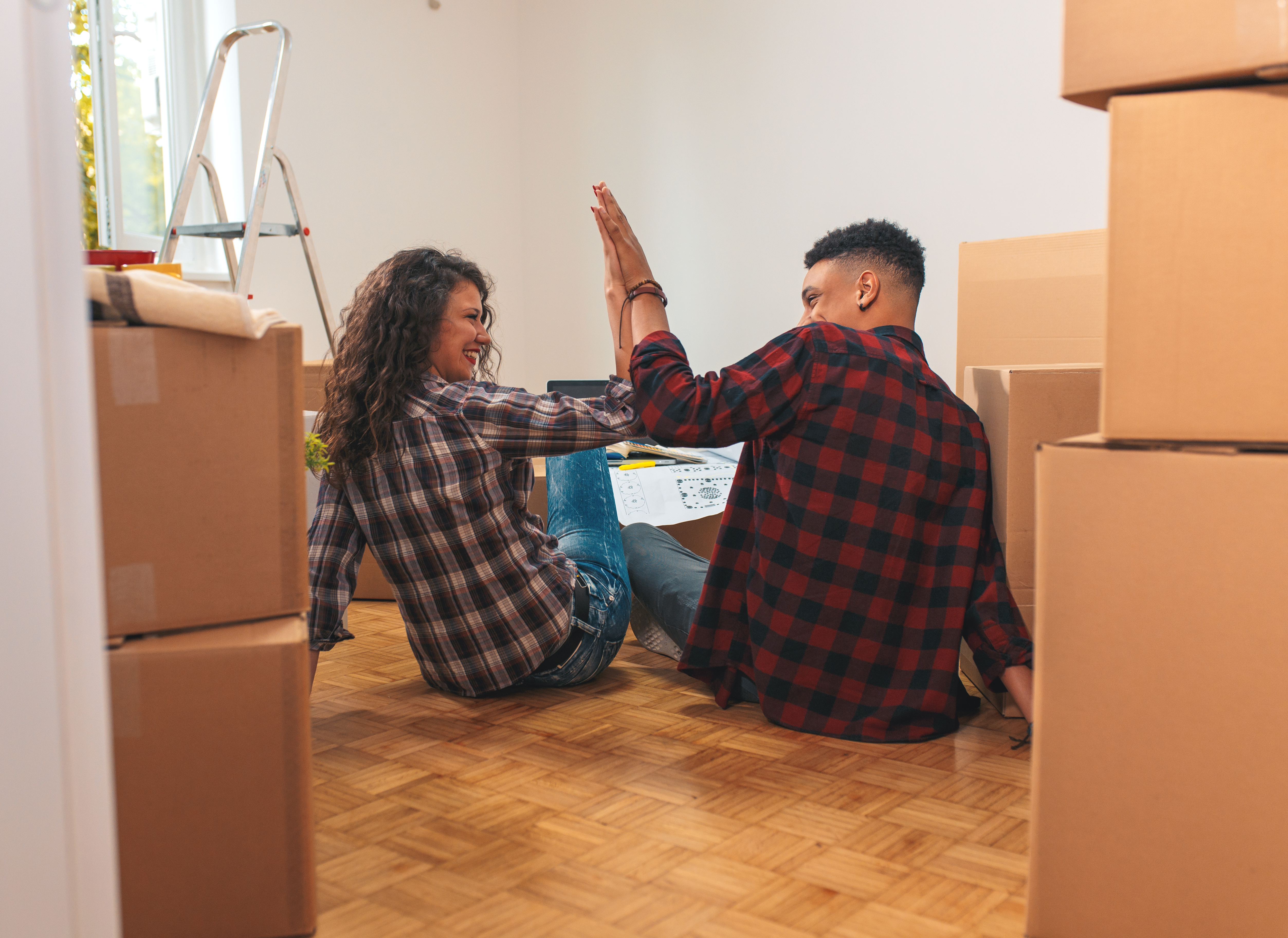 Man and woman high-fiving in the middle of moving boxes